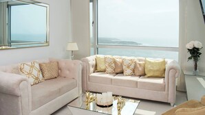 A modern living room with two sofas, a glass coffee table, and a view of the sea. - 1 Bedroom Sunset Luxury Apartment Private Jacuzzi (Cartagena)