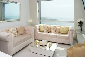 A modern living room with two sofas, a glass coffee table, and a view of the sea. - 1 Bedroom Sunset Luxury Apartment Private Jacuzzi (Cartagena)