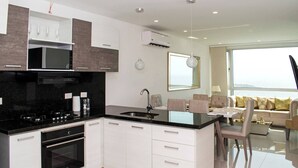 A modern kitchen with a central island, built-in oven, and a dining area with a table and chairs. - 1 Bedroom Sunset Luxury Apartment Private Jacuzzi (Cartagena)