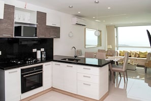 A modern kitchen with a central island, built-in oven, and a dining area with a table and chairs. - 1 Bedroom Sunset Luxury Apartment Private Jacuzzi (Cartagena)