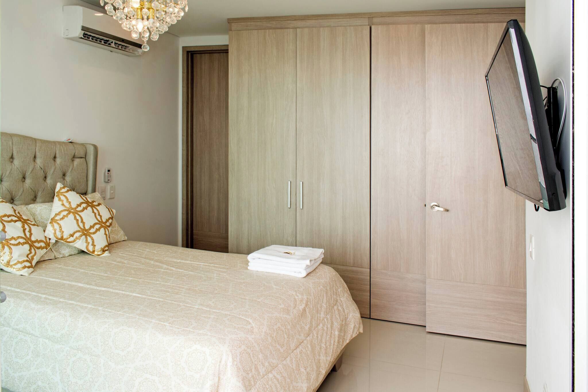 Ein Schlafzimmer mit Bett, Kleiderschrank, Fernseher und Klimaanlage.