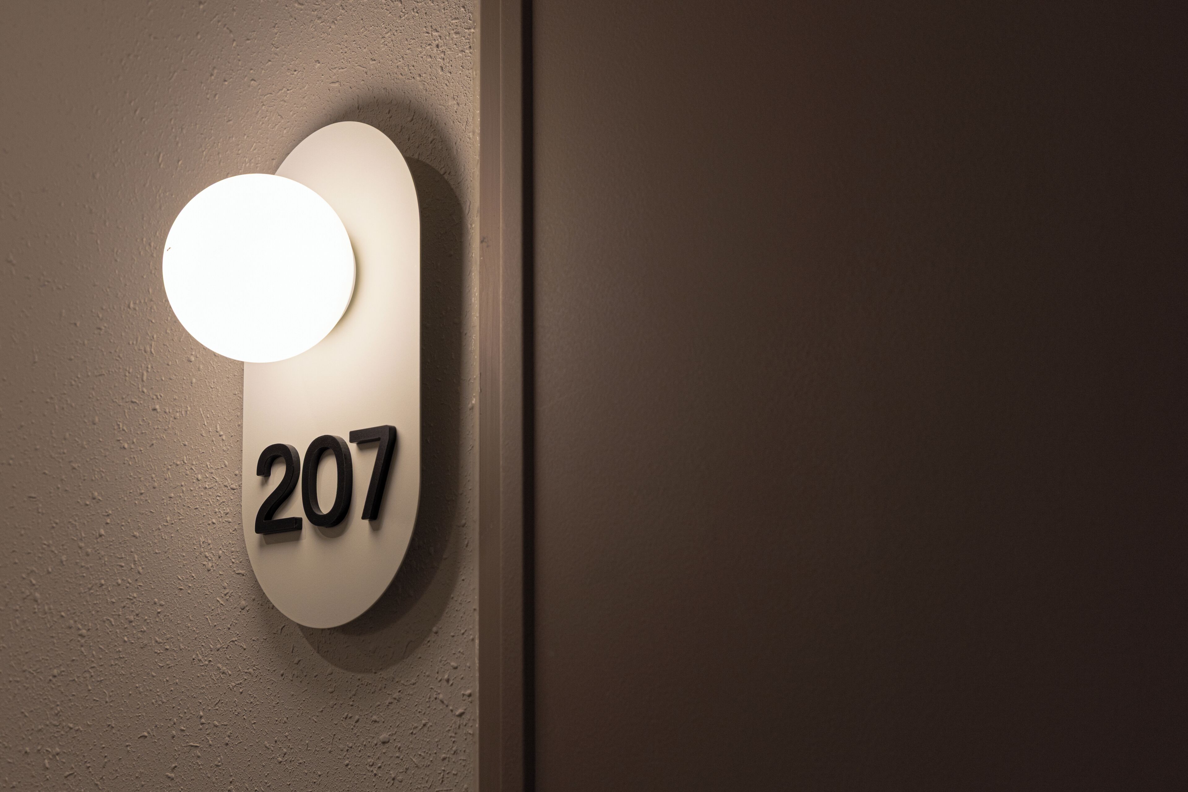Una lámpara de pared con el número '207', indicando una habitación o lugar.