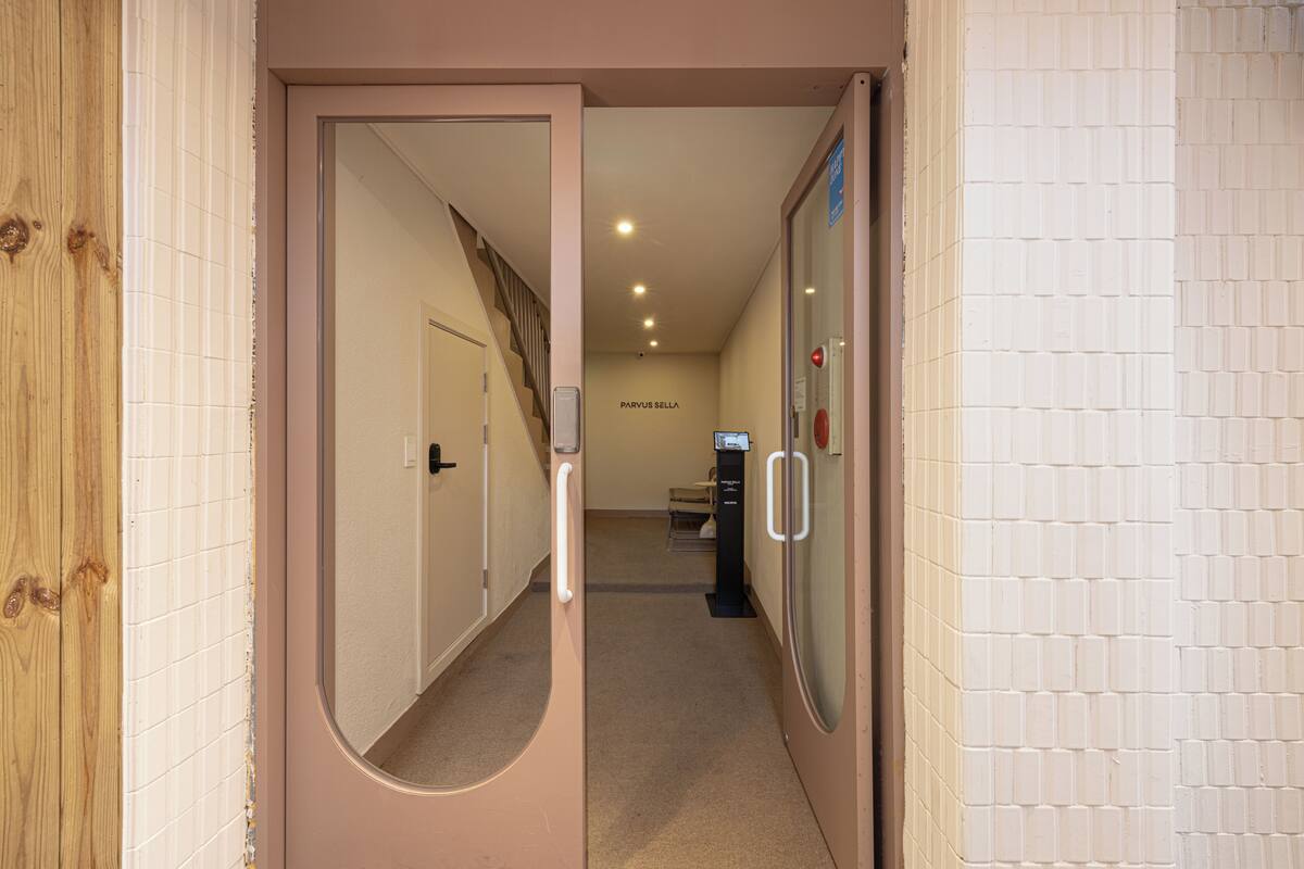 Un pasillo con una puerta de madera, un espejo, una máquina expendedora y un cartel que dice 'PARVUS SALLA'.