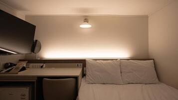Habitación de hotel con cama, escritorio, silla y televisión de pantalla plana montada en la pared.