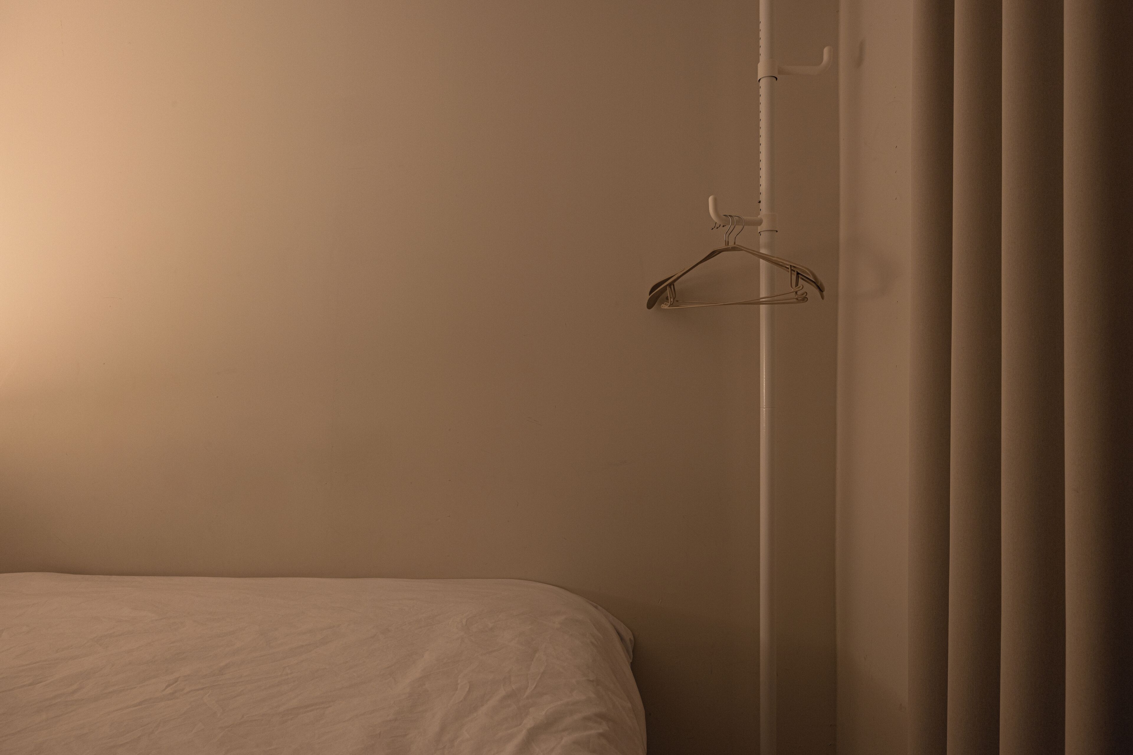 Une chambre à coucher avec un lit, un luminaire suspendu et un rideau.