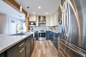 A modern kitchen with stainless steel appliances, wooden beams, and a central island.
