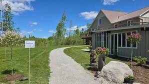 A gravel driveway leading to a house with a porch, a welcome sign, and a well-maintained lawn. - Campfire, Privacy, Stargazing minutes to Beaches/Orillia/Casino Rama (Orillia)