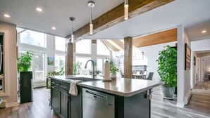 A modern kitchen with a large island, wooden beams, and large windows. - Campfire, Privacy, Stargazing minutes to Beaches/Orillia/Casino Rama (Orillia)