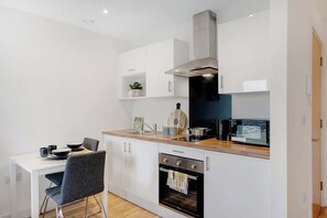 Eine moderne Küche mit weißen Schränken, einer Holz Arbeitsplatte, einem eingebauten Backofen und einer Mikrowelle.