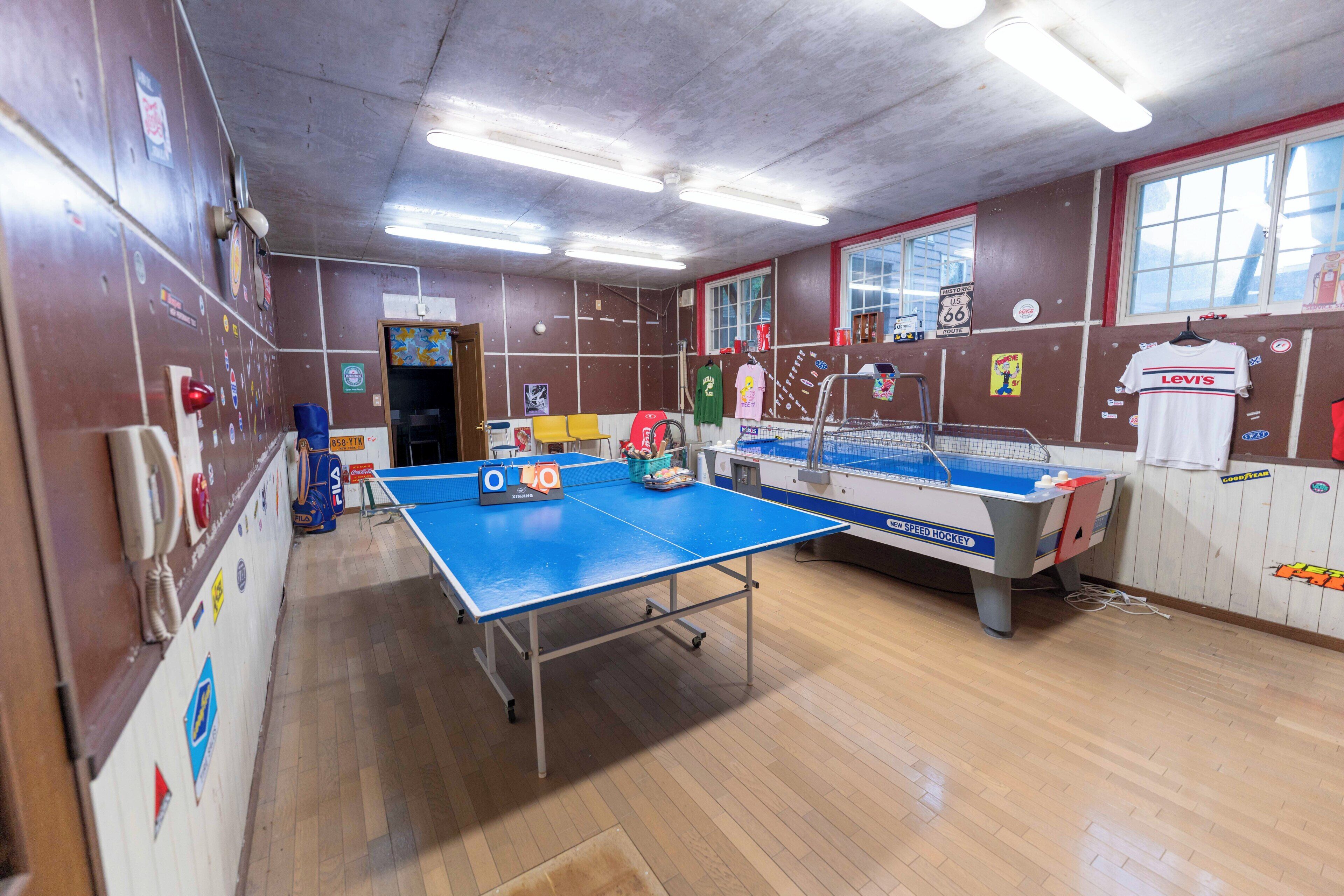 A room with a ping pong table, a pool table, and various sports memorabilia on the walls.
