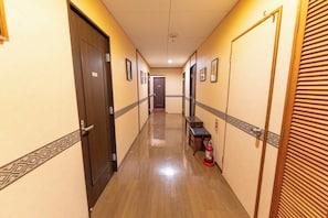 A hotel hallway with wooden doors, a bench, and a fire extinguisher.