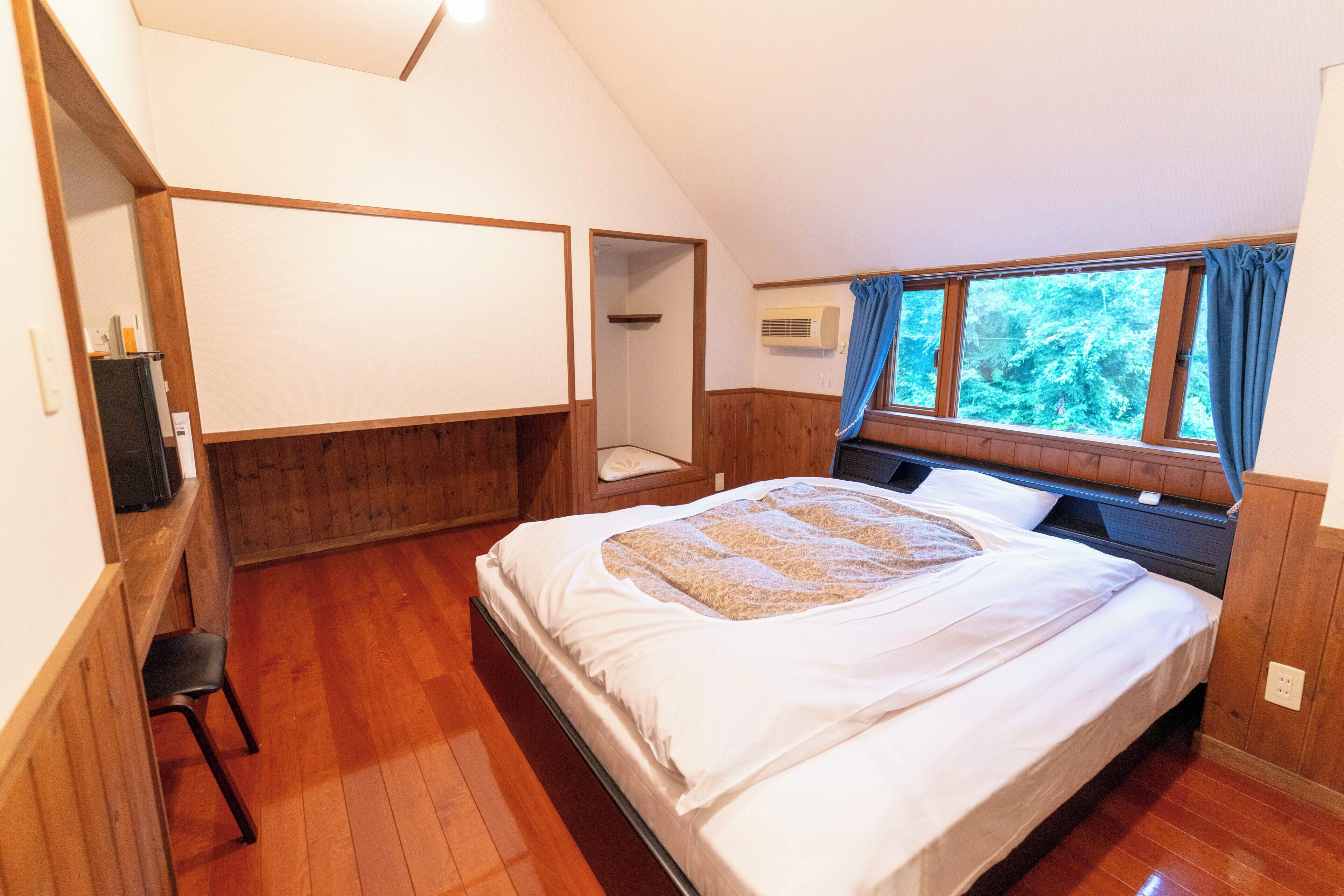 Un dormitorio con cama, escritorio y ventana con cortinas.