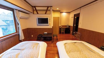 Una habitación con dos camas, televisión, escritorio y una silla.
