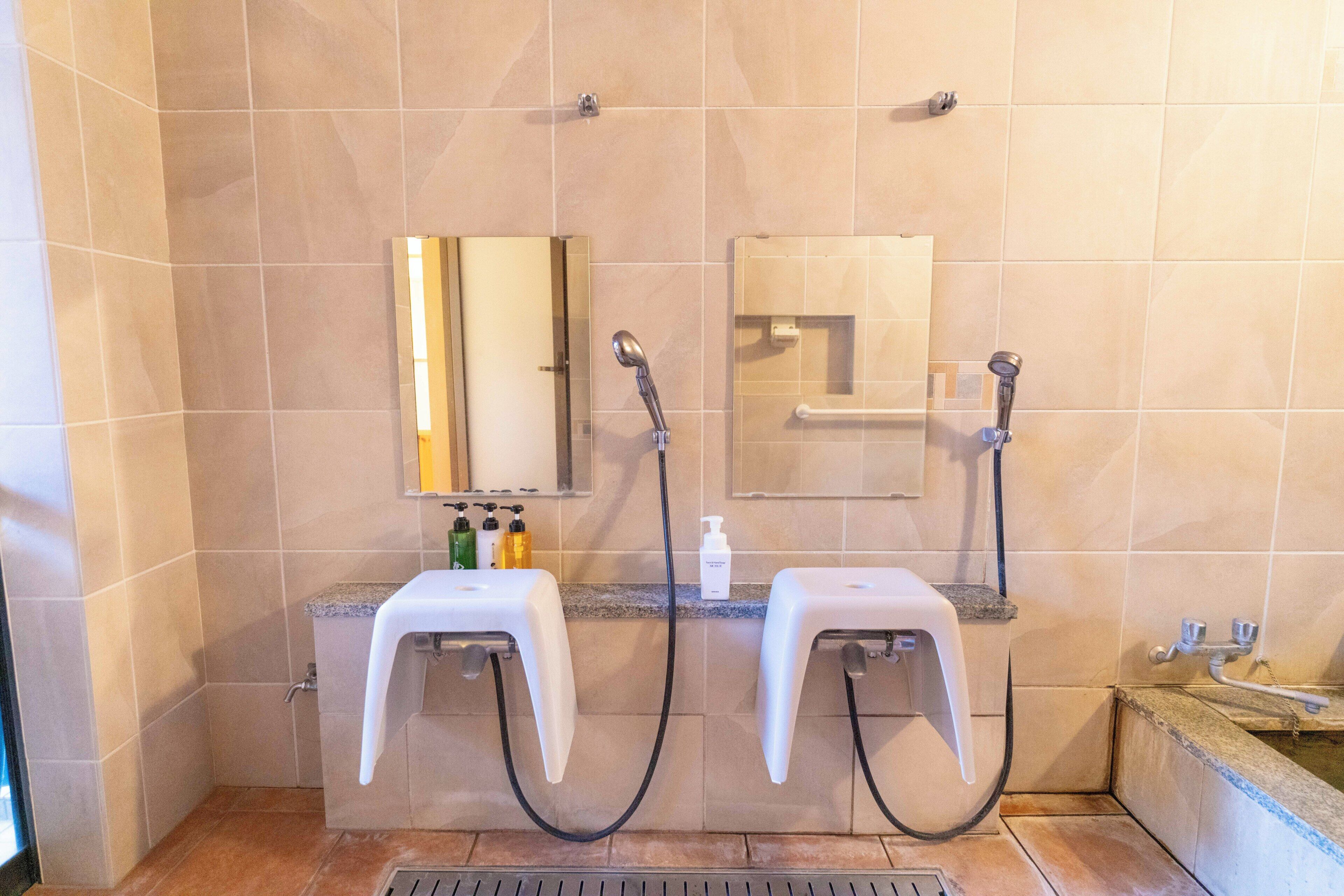 A bathroom with two sinks, a mirror, a shower, and a hand dryer.