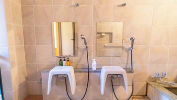 A bathroom with two sinks, a mirror, a shower, and a hand dryer.
