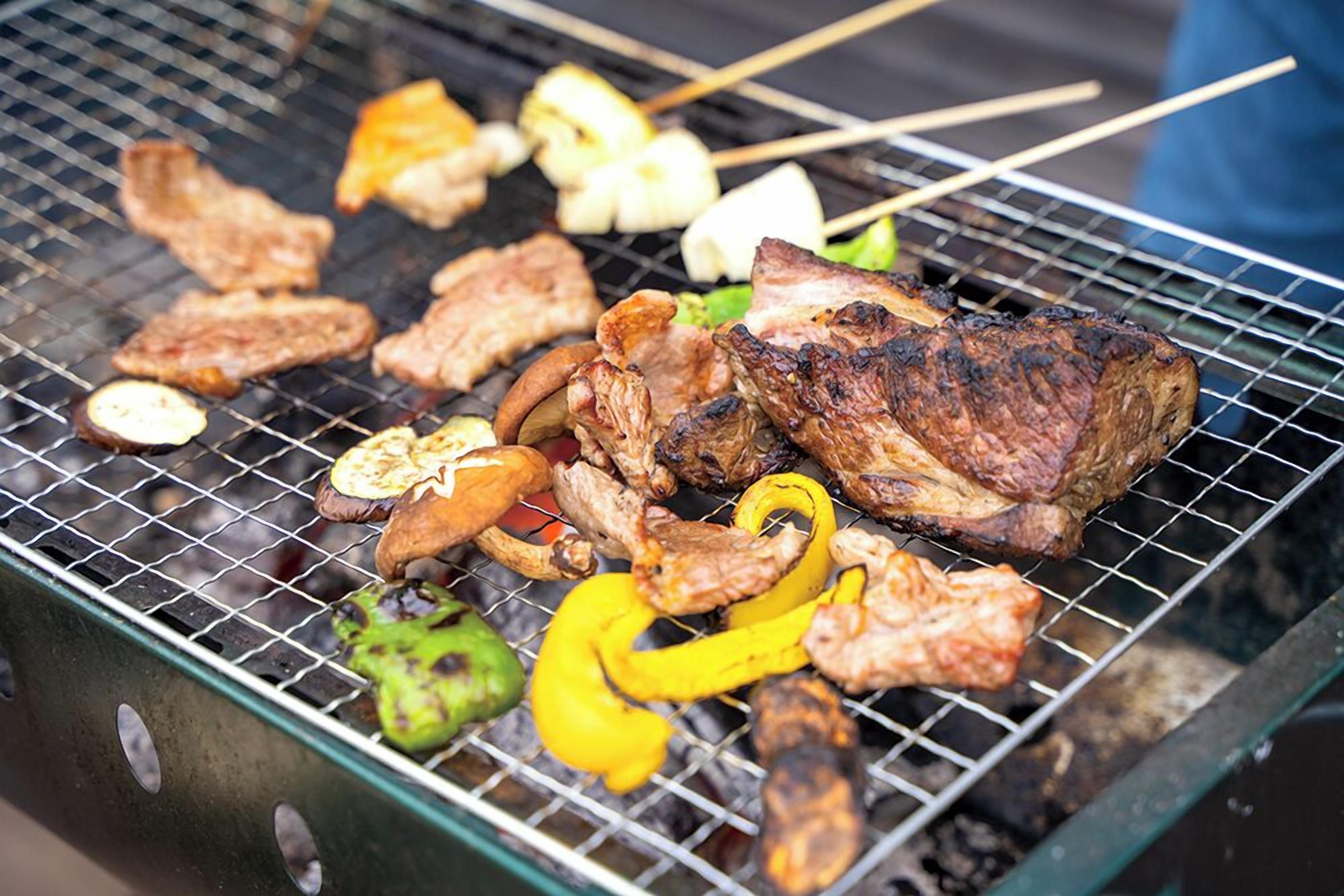 A grill with various meats and vegetables being cooked.