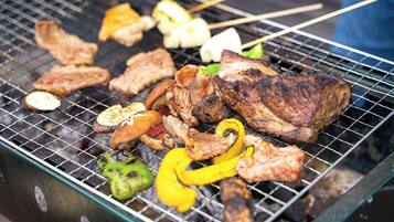 A grill with various meats and vegetables being cooked.
