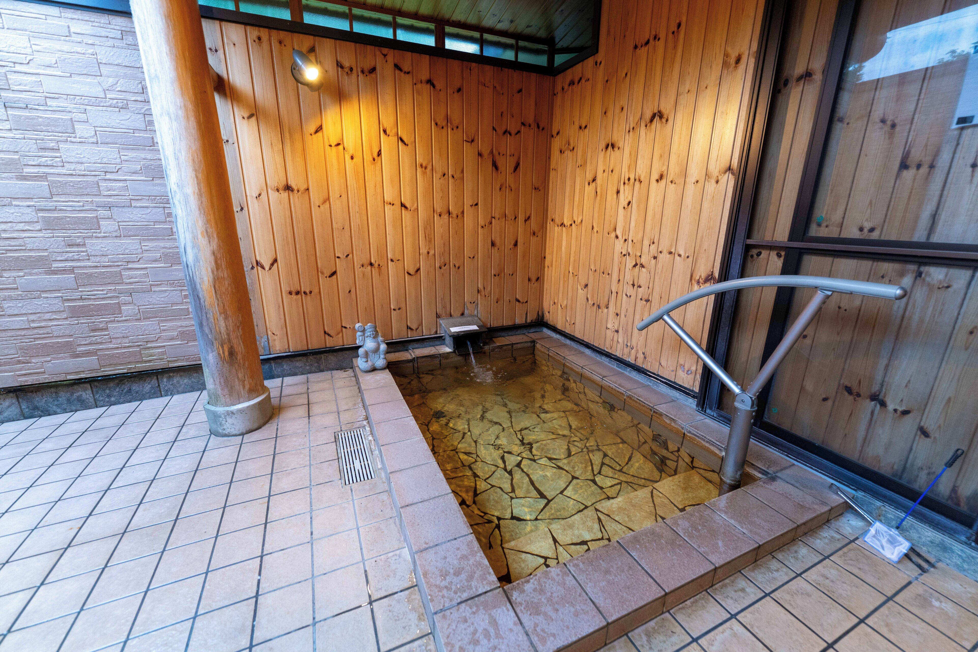 Una sauna de fusta amb terra de rajola i un banc metàl·lic.