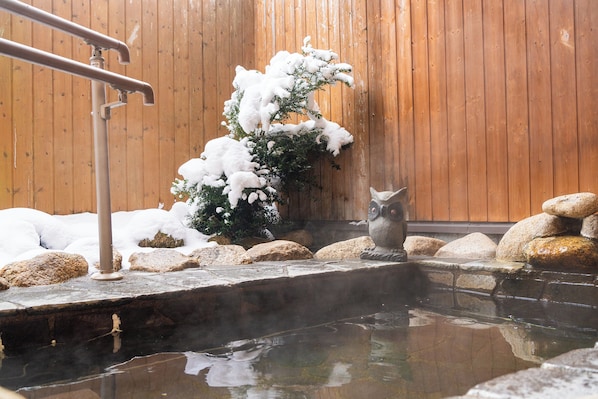 A hot spring area with a wooden wall, rocks, and a stone ledge.