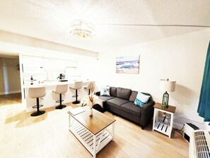 A modern living room with a sofa, coffee table, and a dining area with chairs. - Cozy 1-bedroom apartment with full kitchen in Daytona Beach (Daytona Beach)
