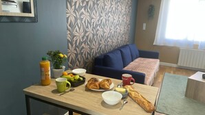 Un coin repas avec une table mise pour le petit-déjeuner, un canapé et une fenêtre avec des rideaux.