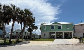 A green building with a covered entrance and a gravel driveway.