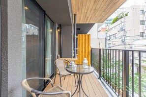 Ein Balkon mit Korbstühlen, einem Glastisch und Blick auf die Stadtlandschaft.