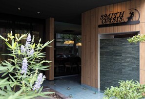 The exterior of Smith Oasis Guest House with a wooden facade, a signboard, and a glass door entrance. - Designer Apartment with Balcony, Walk to Dotonbori, Shinsaibashi & Kuromon Mkt (大阪市)
