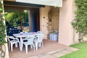 Eine Terrasse im Freien mit Tisch und Stühlen, einer Steinmauer und einem überdachten Bereich.
