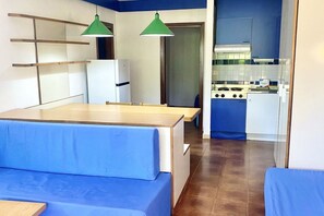 Eine kleine Küche mit Herd, Kühlschrank und hängenden, grünen Pendelleuchten.