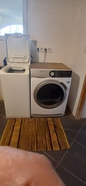 A compact washing machine and dryer unit in a small laundry room with a striped rug on the floor. - Prestige of Saint Paul de Varces (Saint-Paul-de-Varces)