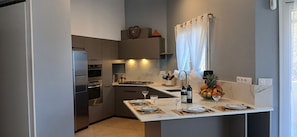 A compact kitchen with modern appliances, a dining area with a table set for two, and a fruit bowl on the counter. - Prestige of Saint Paul de Varces (Saint-Paul-de-Varces)