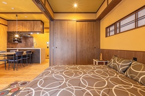 A bedroom with a large bed, a wooden headboard, a nightstand, and a window with blinds. - Stylish Apartment with Balcony, Walk to Dotonbori, Shinsaibashi, & Kuromon Mkt (大阪市)