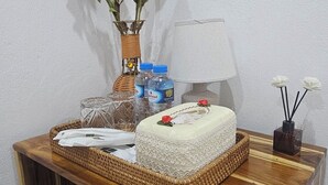 A wooden console table with a cake, a lamp, a vase with flowers, and a basket. - Loaviengluabgprabang guesthouse (Luang Prabang)