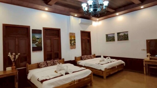 A room with two wooden beds, a chandelier, wooden ceiling beams, and a tiled floor. - Loaviengluabgprabang guesthouse (Luang Prabang)