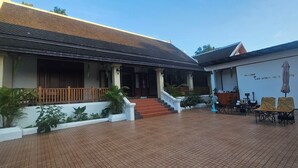 A traditional building with a tiled roof, a covered porch, and a staircase leading to the entrance. - Loaviengluabgprabang guesthouse (Luang Prabang)