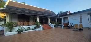 A traditional building with a tiled roof, a covered porch, and a staircase leading to the entrance. - Loaviengluabgprabang guesthouse (Luang Prabang)