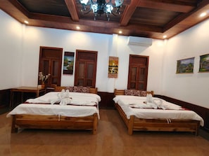 Une chambre d’hôtel avec deux lits en bois, un plafond en bois et un lustre.