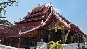 A traditional multi-tiered temple with ornate golden decorations and a red roof. - Loaviengluabgprabang guesthouse (Luang Prabang)