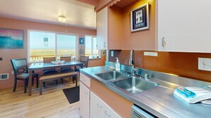 Una cocina con un lavamanos doble, una zona de comedor con mesa y sillas, y vistas por la ventana.
