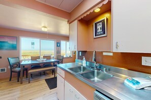 Eine Küche mit doppeltem Spülbecken, ein Essbereich mit Tisch und Stühlen sowie ein Ausblick durch das Fenster.