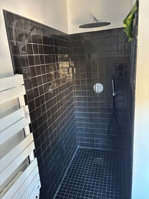 A bathroom with black tiled walls, a shower, and a white towel rack. - Very pleasant house with swimming pool, garden, air conditioning - 10 min from the beaches (Pérols)