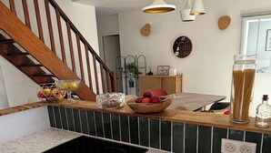 Eine Küche mit Einbauherd, Holztreppe und Pendelleuchten.