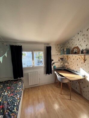 A compact room with a bed, a desk, a radiator, a window, and a wall with a tree pattern. - Very pleasant house with swimming pool, garden, air conditioning - 10 min from the beaches (Pérols)