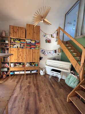 A room with wooden bookshelves, a piano, a wooden staircase, and a hanging light fixture. - Very pleasant house with swimming pool, garden, air conditioning - 10 min from the beaches (Pérols)