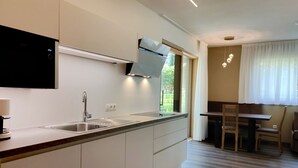 A modern kitchen with a built-in stove, a sink, and a dining area with a table and chairs. - Highlight Apartments: Ap. Harmony with garden access, loggia and Mobil Card incl. (Sankt Pauls)