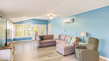 A spacious living room with a large sectional sofa, a chair, a small table, and a ceiling fan.