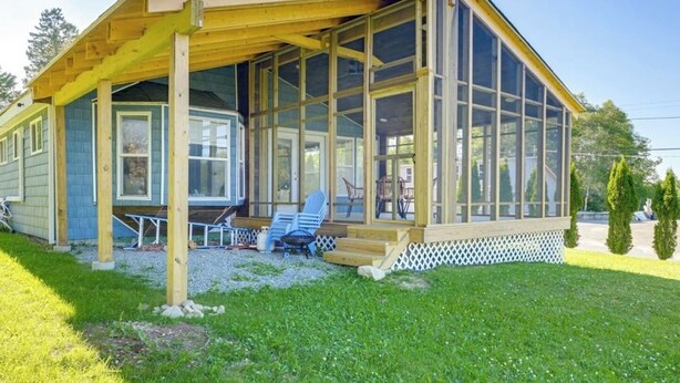 A single-story building with a covered porch, large windows, and a small outdoor seating area.