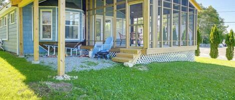 A single-story building with a covered porch, large windows, and a small outdoor seating area.