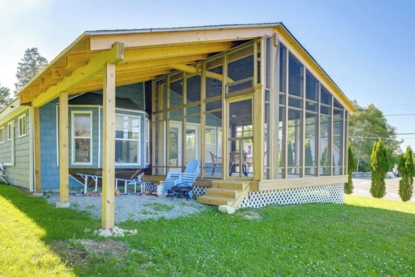 A single-story building with a covered porch, large windows, and a small outdoor seating area.